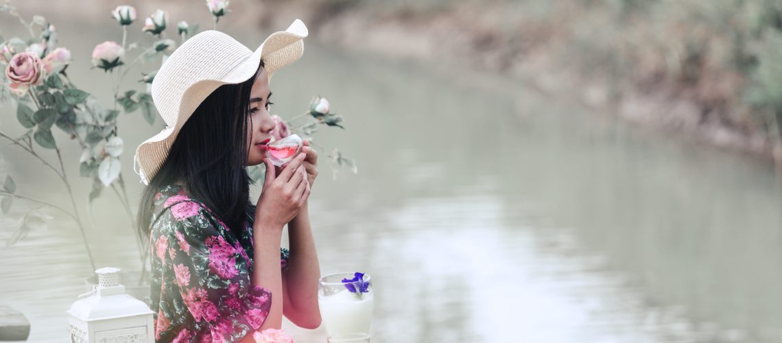 The girl in red floral dress that sits tea at the waterfront.